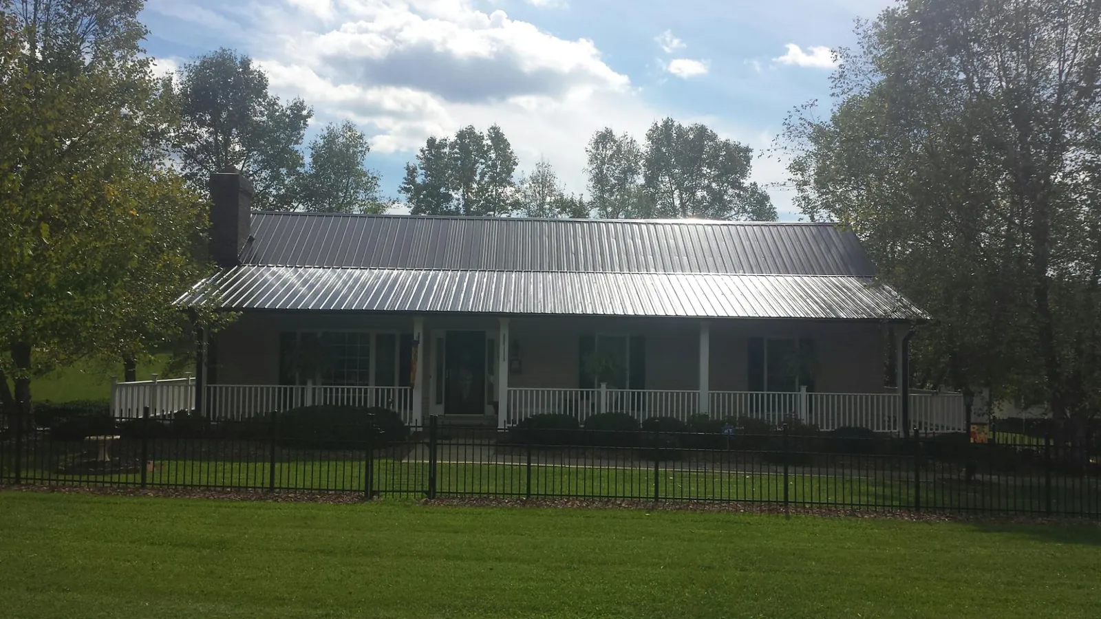Gray metal roof on a brick ranch with a full width front porch — Gutter Guard Installation work by our crew in North Royalton