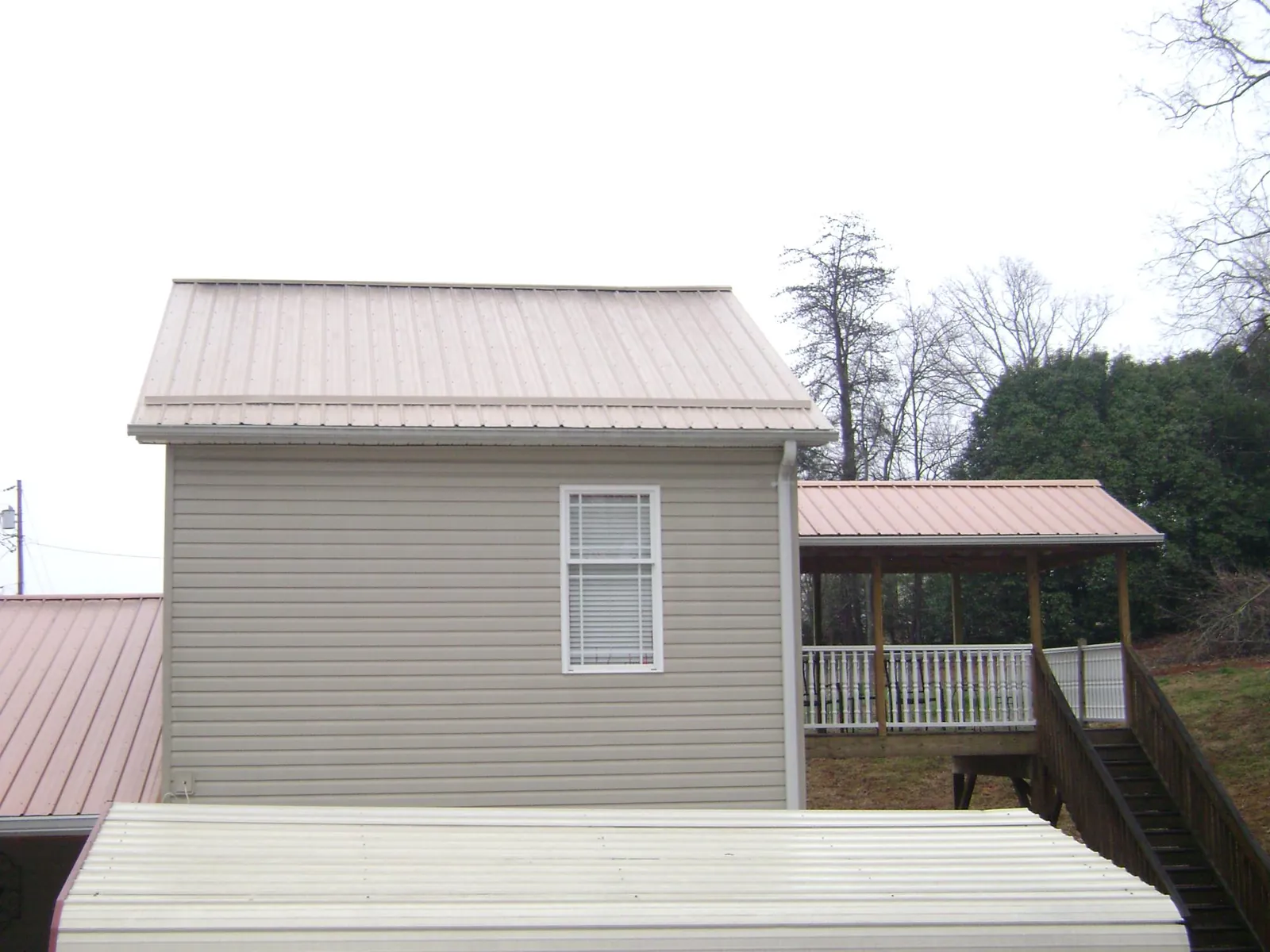 Tan metal roofs on a two story addition and attached porch, from a Roof Replacement job in North Royalton
