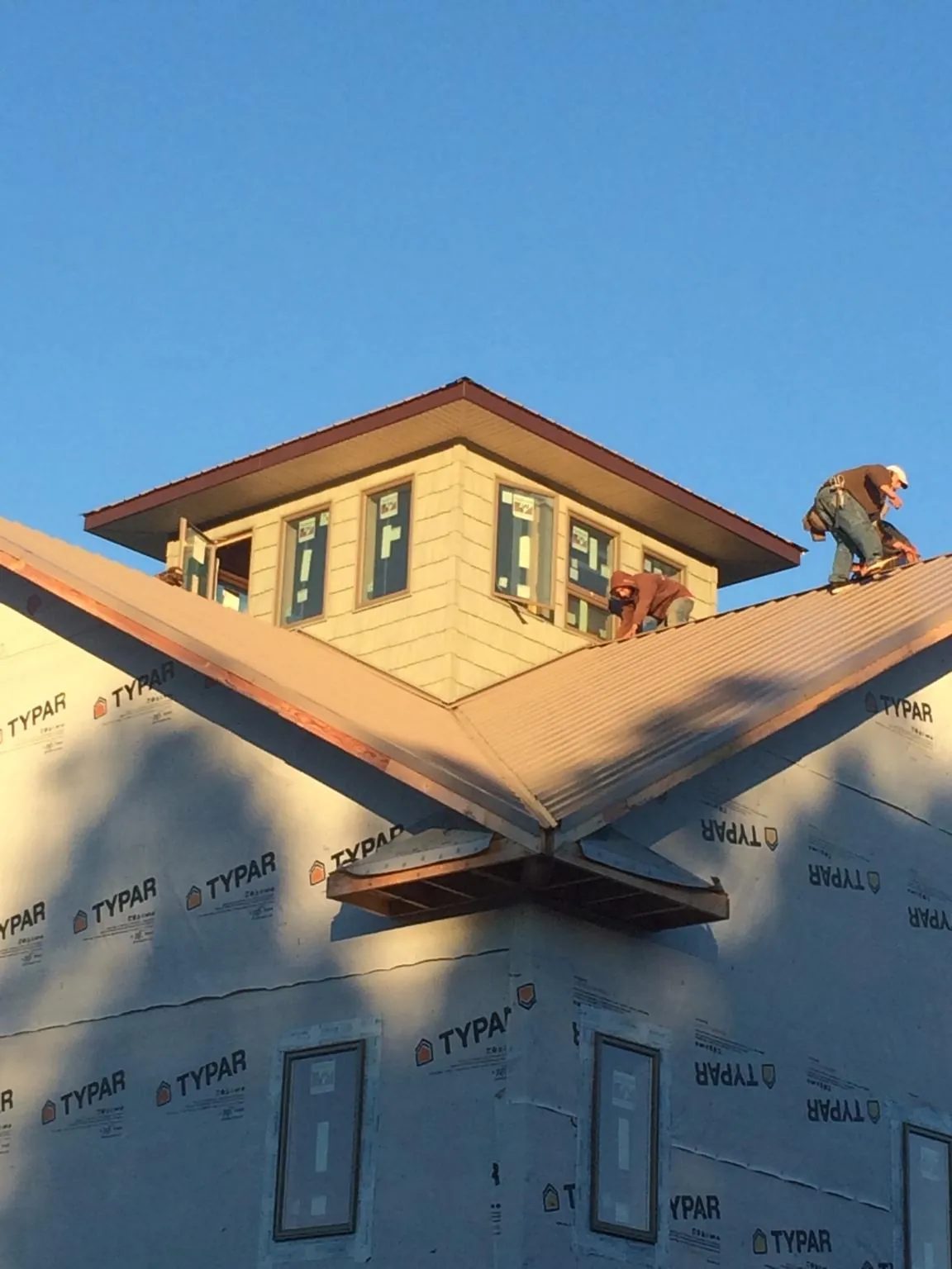 Roofers working around a rooftop cupola on a new metal roof at sunset — Roof Waterproofing in North Royalton by Roofing Brothers